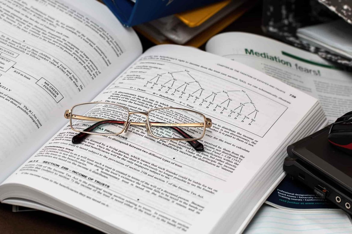 Lunettes de vue posées sur les pages ouvertes d’un livre de droit et de finance détaillant les obligations comptables sci.